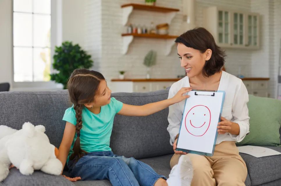 La sicurezza è un programma di vita: mamma mostra alla figlia il disegno di un volto sorridente.